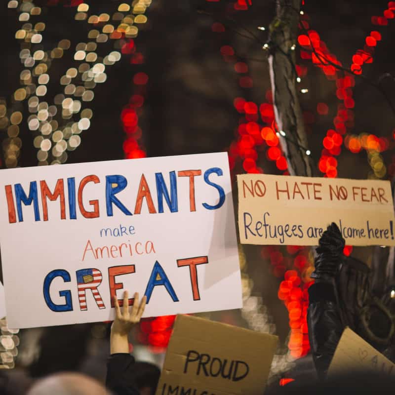 Protesters holding signs reading Immigrants make America Great